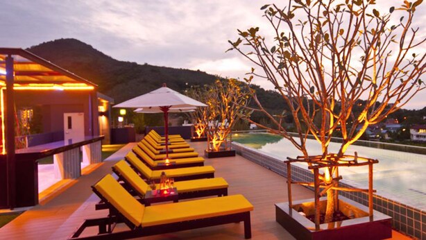 Un área de lounge en la azotea con sillones amarillos y vistas a la piscina.