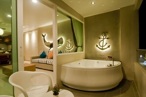 Un baño moderno con una bañera grande, un box de ducha de vidrio y una zona de estar con vistas a la ciudad.