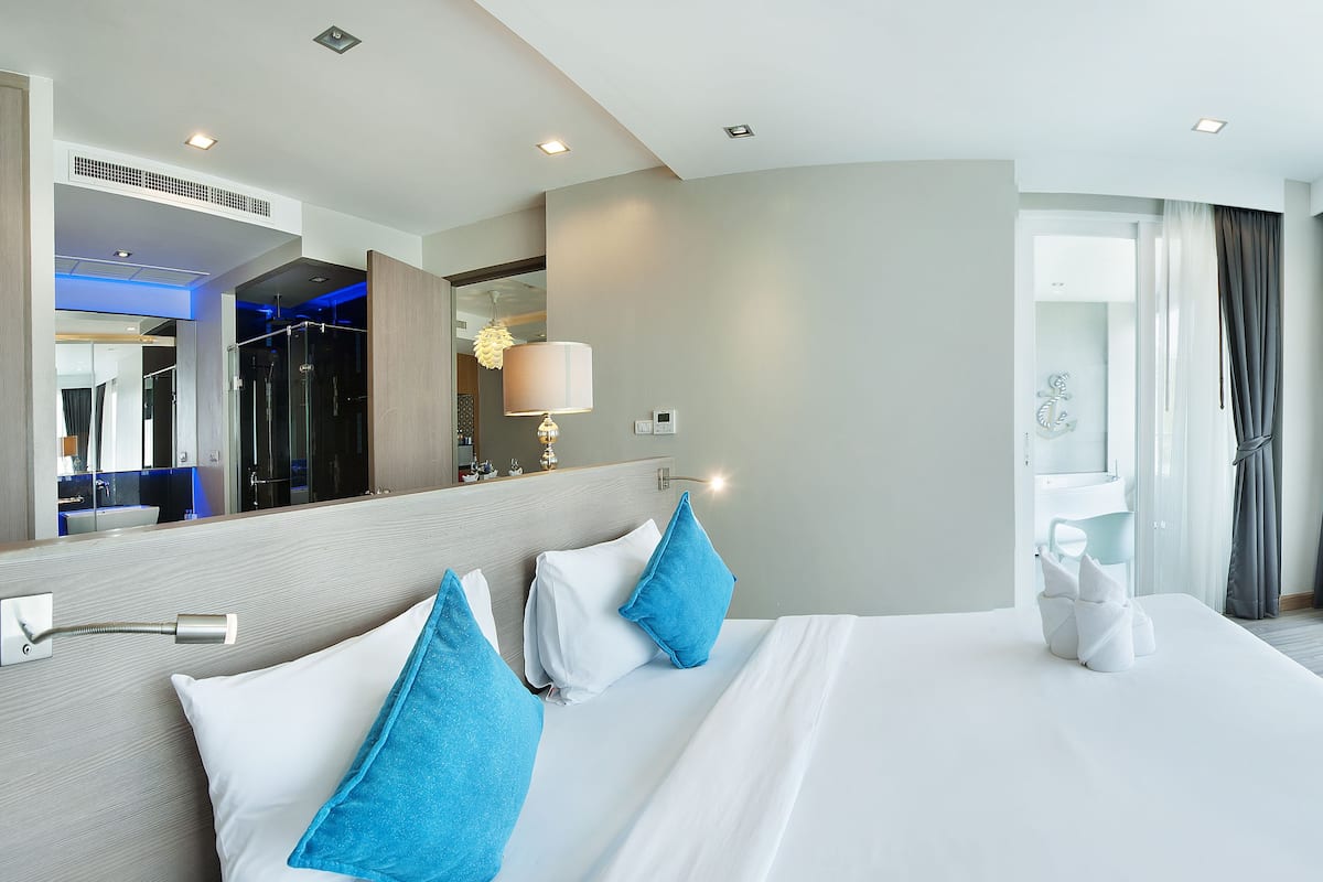 Une chambre d’hôtel avec un grand lit, une salle de bain avec un miroir et une vue sur l’extérieur.
