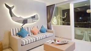 Una sala de estar moderna con un sofá, cojines, una mesa de centro y una escultura de ballena montada en la pared.