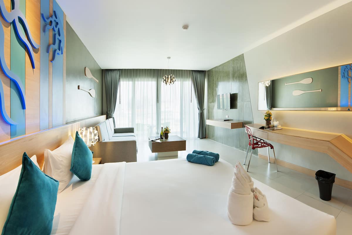 Une chambre d’hôtel moderne équipée d’un grand lit, d’un bureau, d’une chaise et d’un téléviseur.