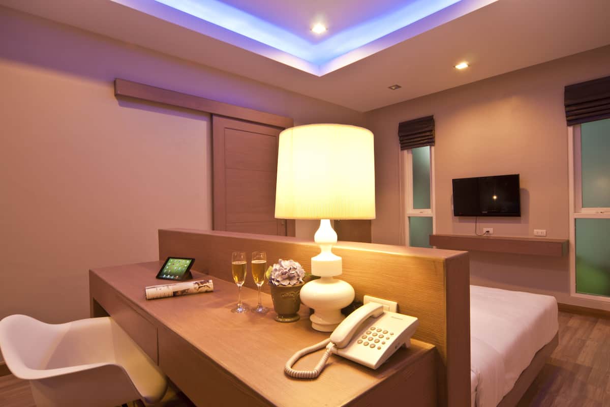 Une chambre d’hôtel équipée d’un bureau, d’une lampe, d’un téléphone, d’une télévision et d’un lit.