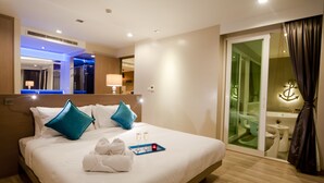 Habitación de hotel con una cama grande, un baño con paredes de vidrio y vistas a la ciudad.