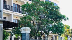 A multi-story hotel with a central courtyard, a large tree, and a sign for 'Hách San Anh Duong Sunshine Hotel'. - Sunshine Hoian Hotel (Da Nang)