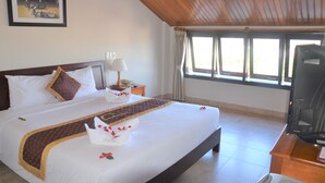 A hotel room with a large bed, a television, a nightstand, a lamp, and a window with curtains. - Sunshine Hoian Hotel (Da Nang)