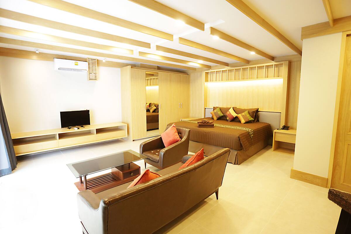 A modern hotel room with a sofa, a bed, a TV, and a desk.