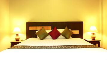 A bed with a wooden headboard, two bedside lamps, and three pillows.
