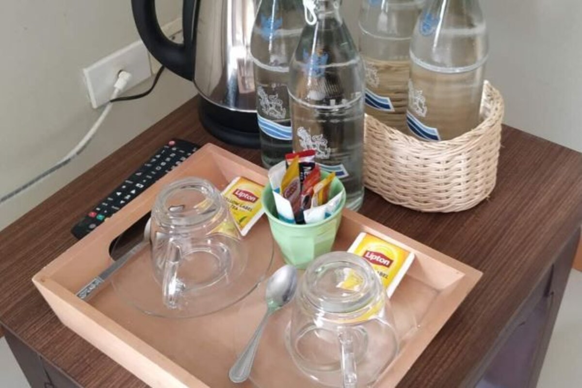 A tray with two clear glasses, a spoon, and Lipton tea packets on a wooden table.