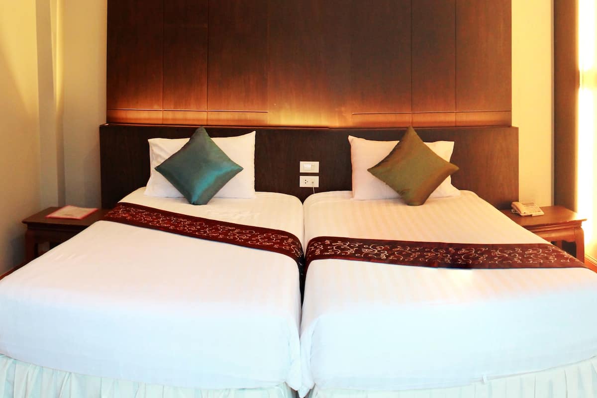 A double bed with a wooden headboard, two pillows, and a decorative bed runner.
