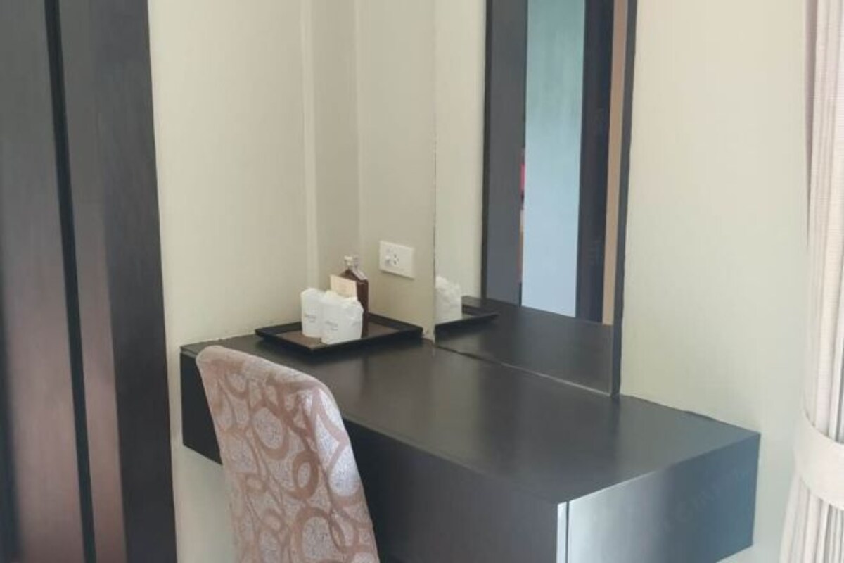 A modern bathroom with a dark countertop, a towel, and a mirror.
