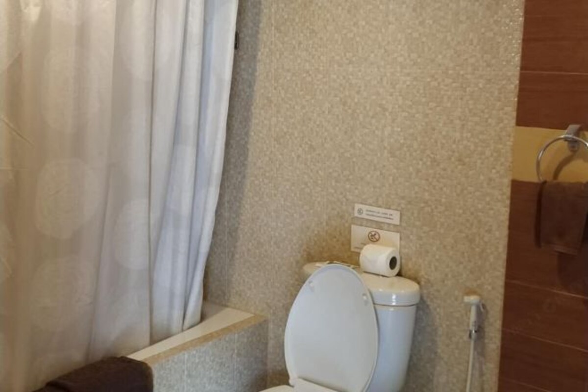 A bathroom with a toilet, a shower curtain, and a towel rack.