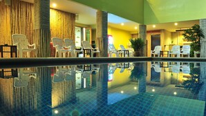 An indoor swimming pool with clear water, surrounded by white chairs and a wooden wall. - Hua Hin White Sand (Hua Hin)