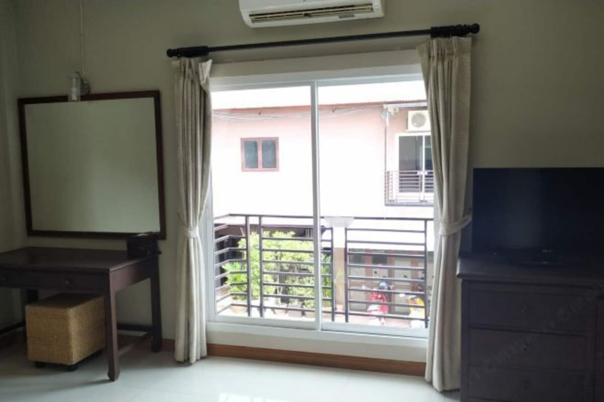 A room with a large window, a TV, a desk, and a dresser.