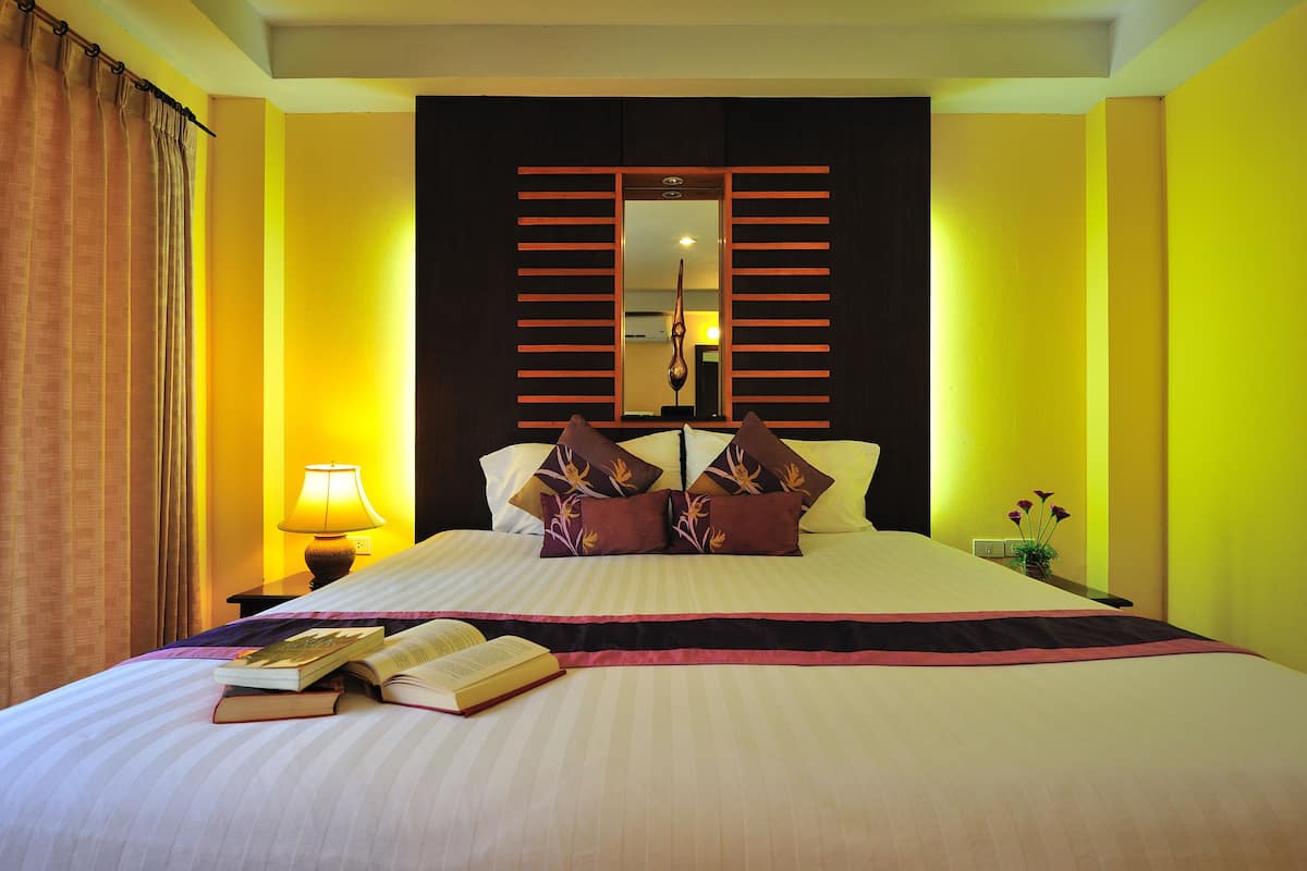 A neatly made bed with a book, a lamp, and decorative pillows.