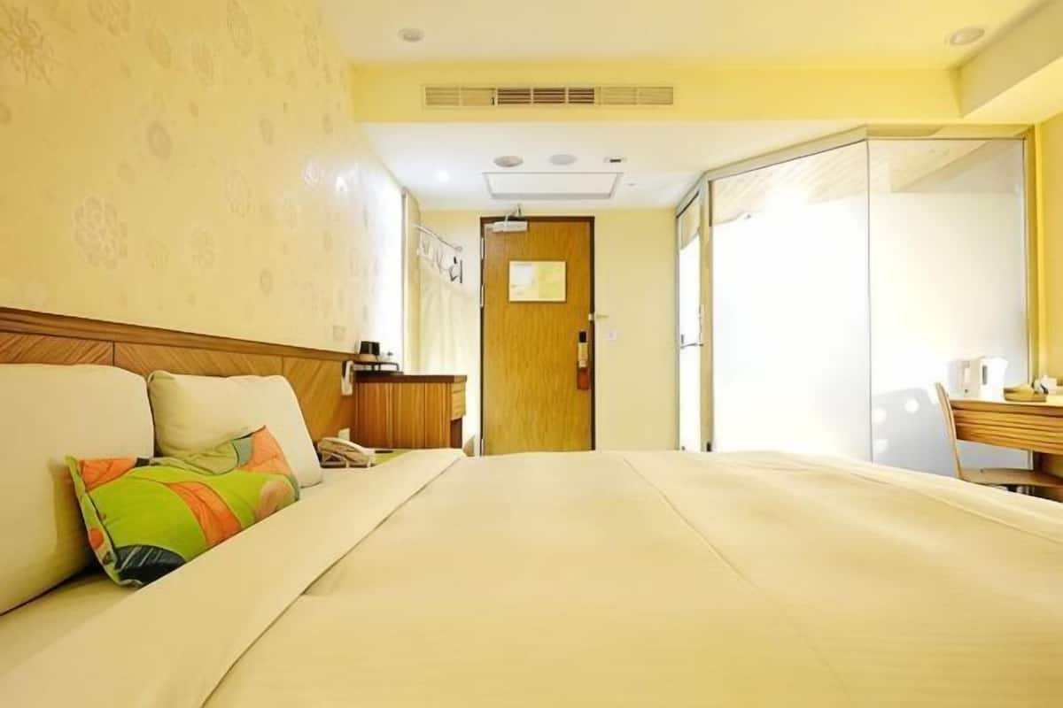 A hotel room with a bed, a sofa, a desk with a chair, and a wardrobe.