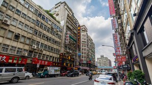 A busy urban street with multiple buildings, some with visible signage indicating businesses and services. - Nagahiro Hotel (Taipei)