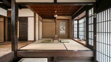 A traditional Japanese room with tatami flooring, sliding doors, and a low wooden ceiling.