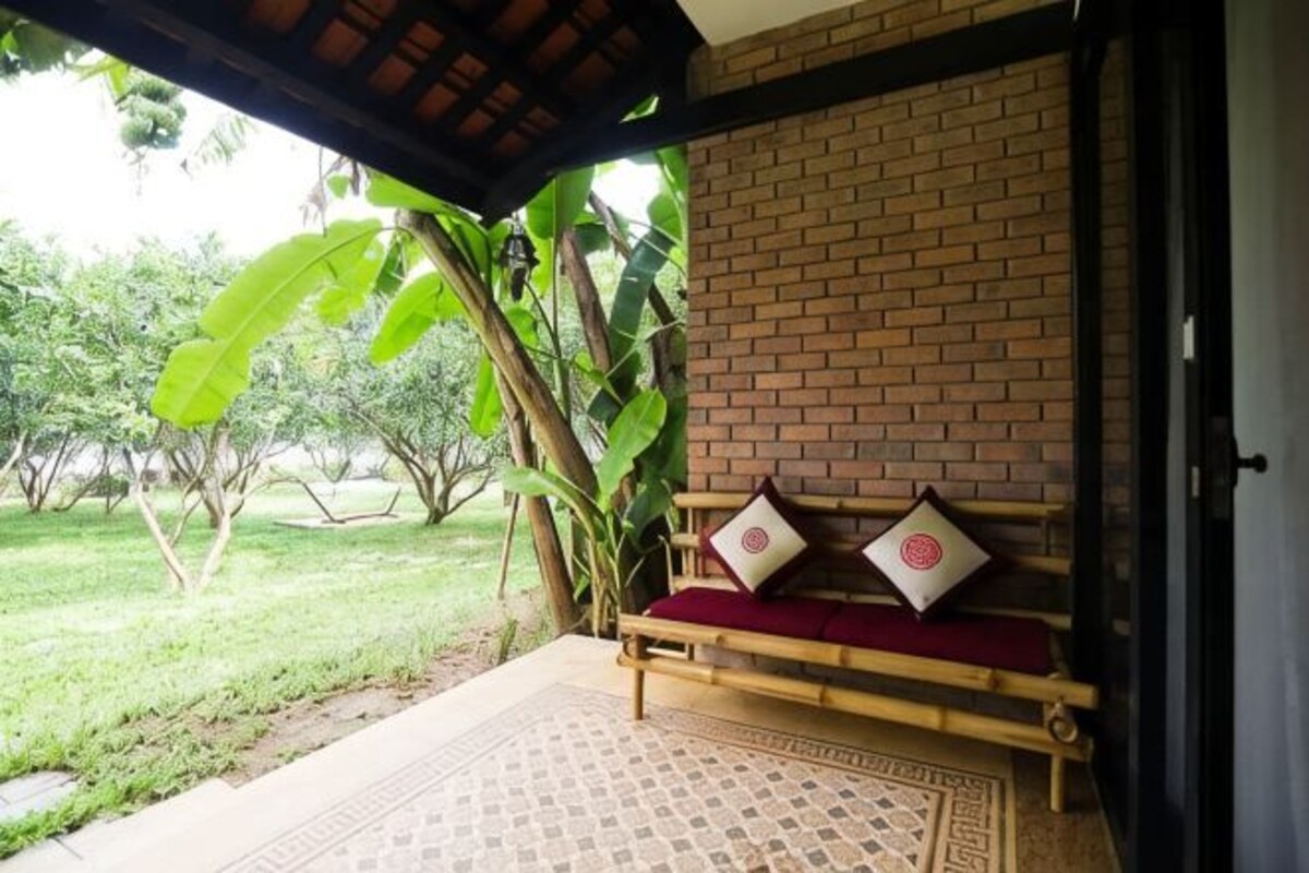 A wooden bench with cushions, a brick wall, and a door.