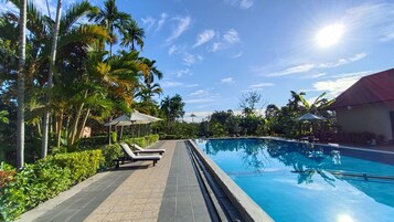 Una piscina al aire libre, sillones reclinables de piscina