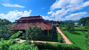 A two-story house with a red roof, surrounded by lush greenery and a clear blue sky. - Hue Riverside Boutique Resort & Spa (Hue)