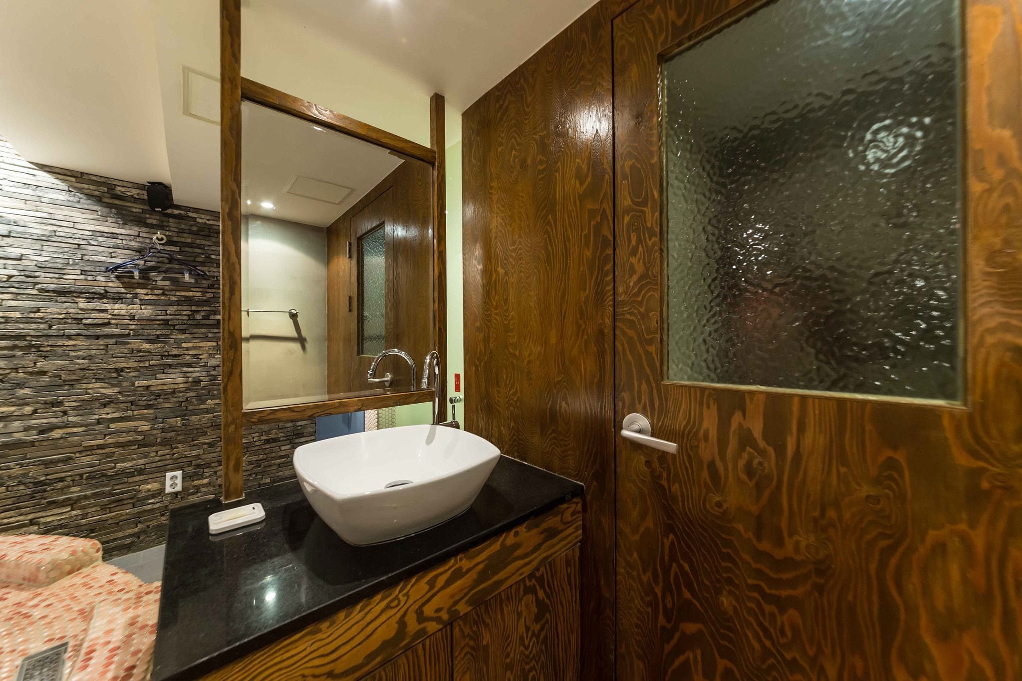 A bathroom with a stone wall, a wooden door, and a white sink.
