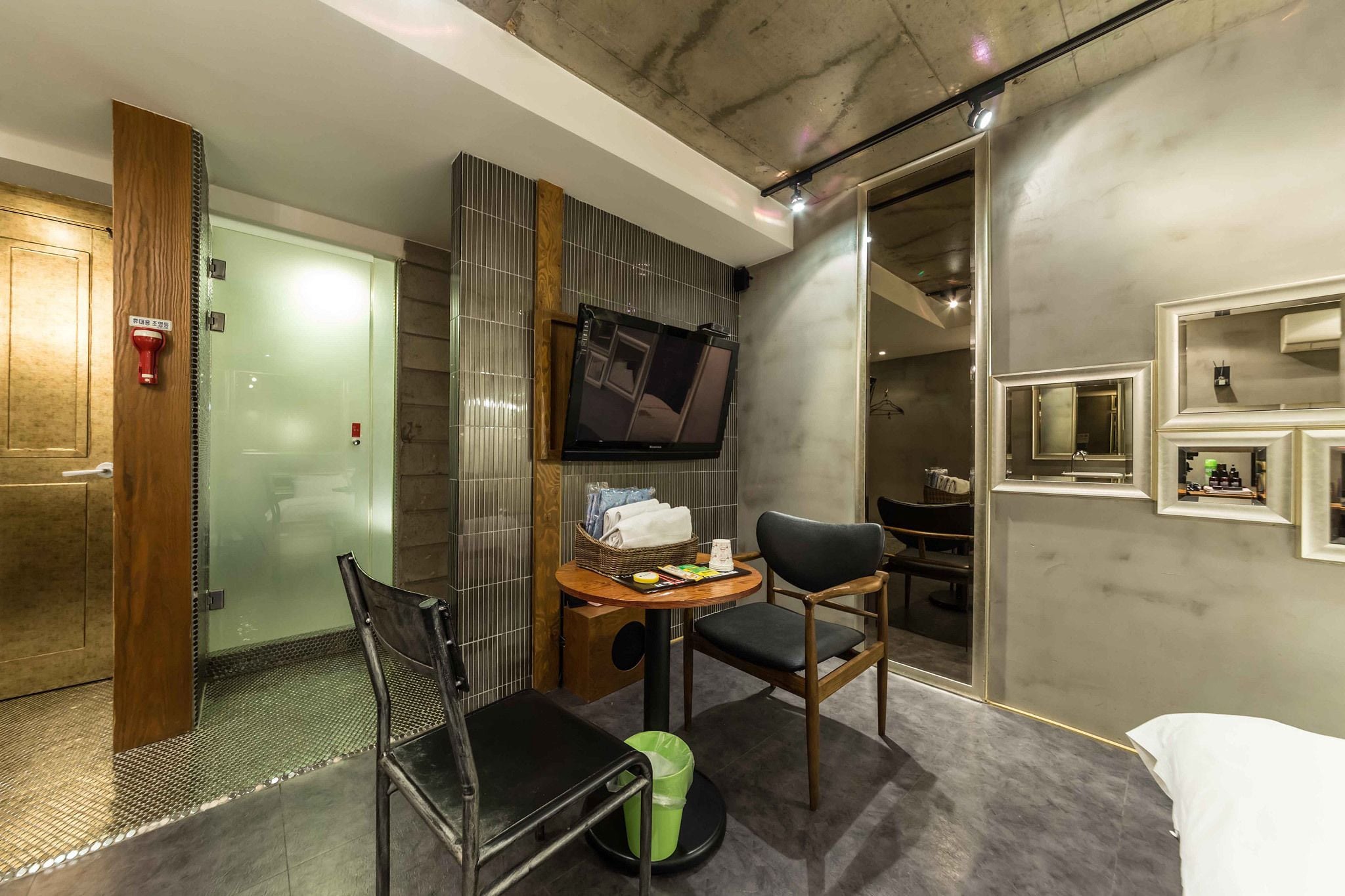 Una habitación de hotel moderna con ducha, una pequeña mesa con silla, televisor y cama.