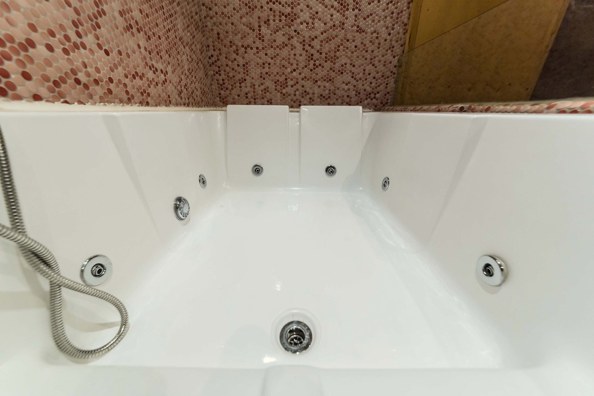 Une baignoire blanche dotée d’un pommeau de douche à main, d’un drain et d’un robinet.