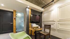 A room with a black door, a blue door, a green chair, a wooden chair, a small round table, and a flat-screen TV mounted on the wall. - Hotel Yaja Yeongdeungpo (Seoul)