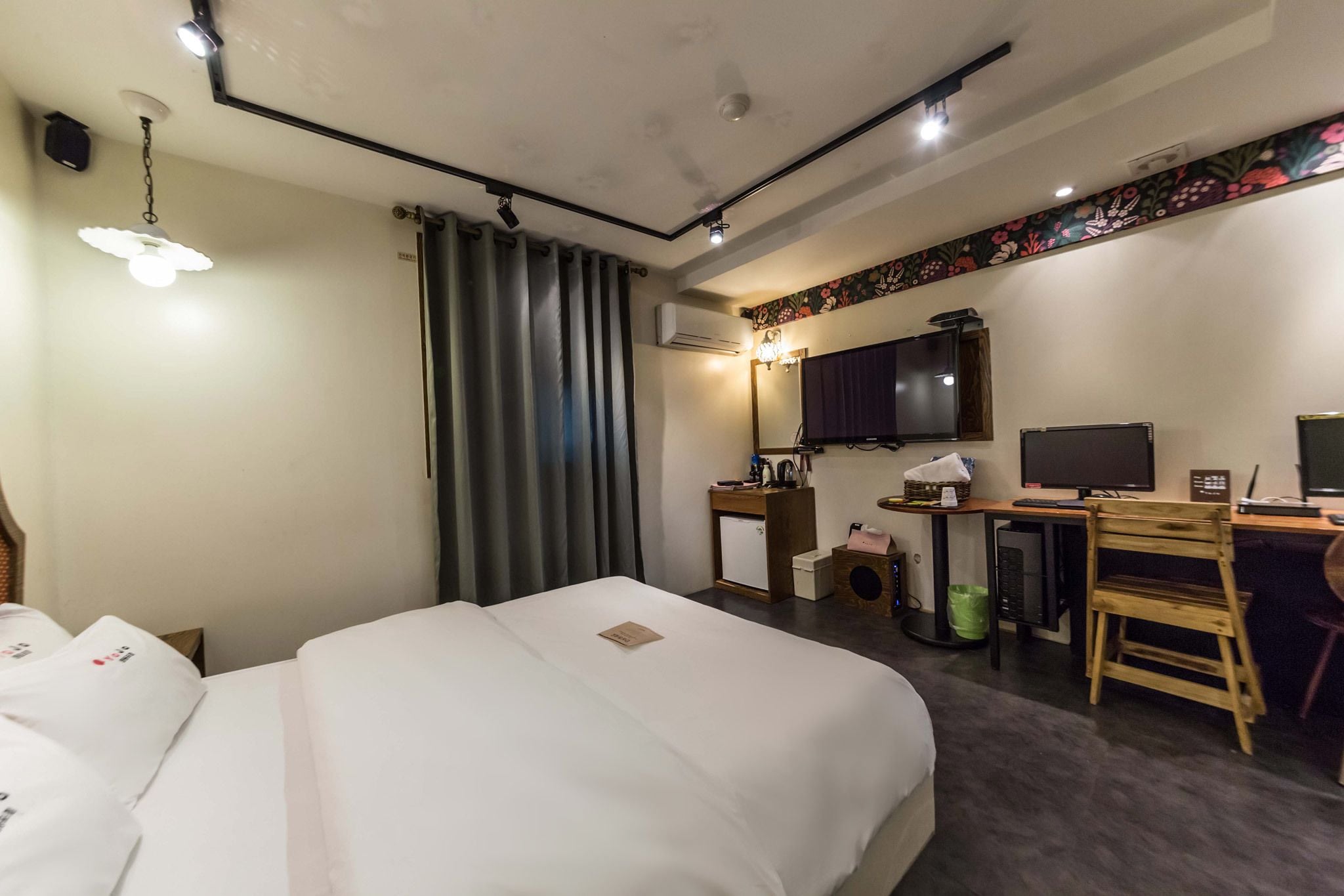 A hotel room with a bed, desk, chair, television, and a small refrigerator.