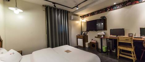 A hotel room with a bed, desk, chair, television, and a small refrigerator.