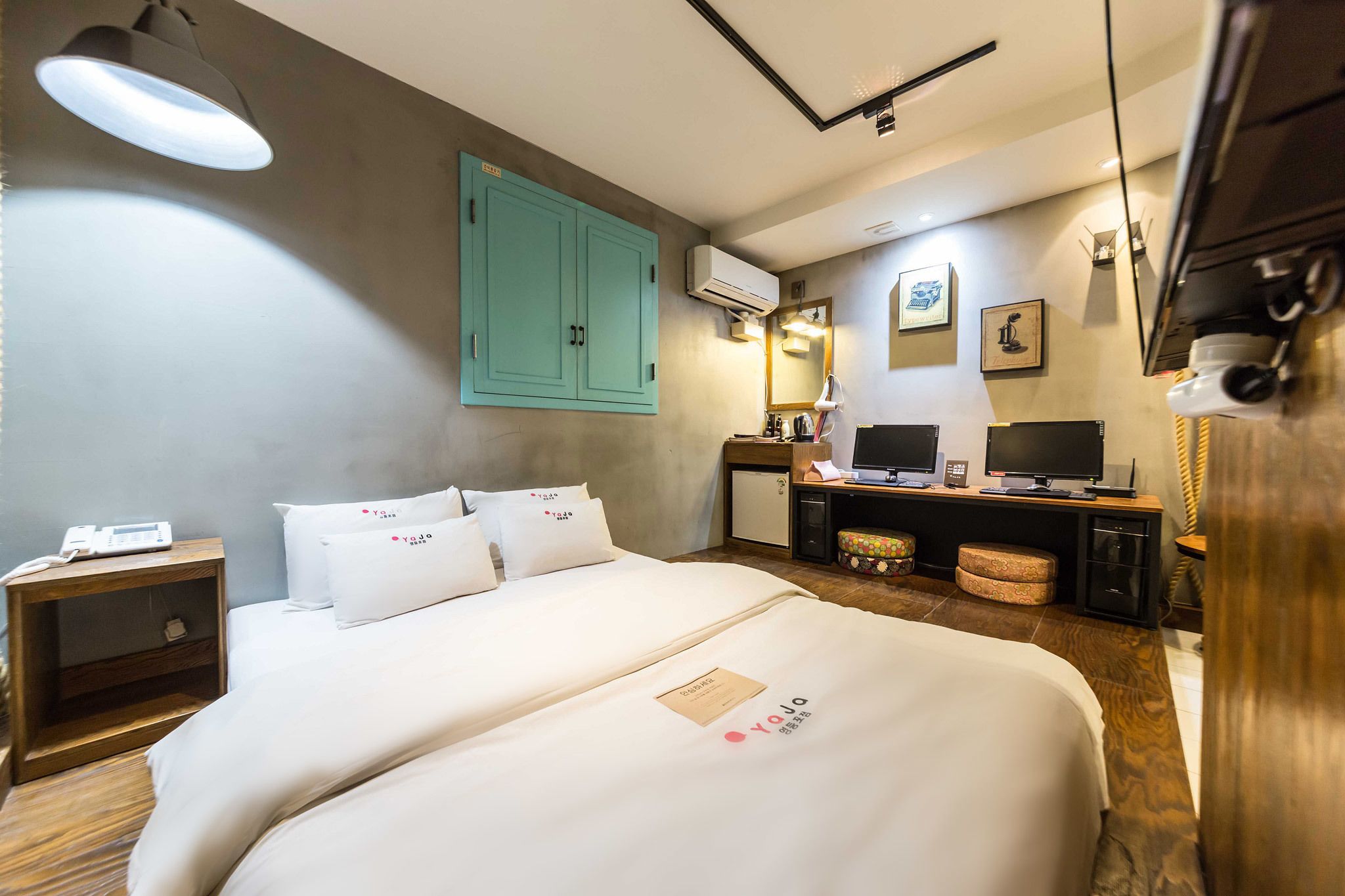 A hotel room with a bed, bedside table, desk, and a television.