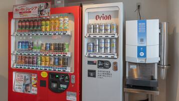 Een automaat met diverse dranken en snacks, een koelkast met blikjes, en een waterdispenser.