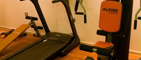 Un gimnasio con cinta de correr, bicicleta estática y máquina de pesas.