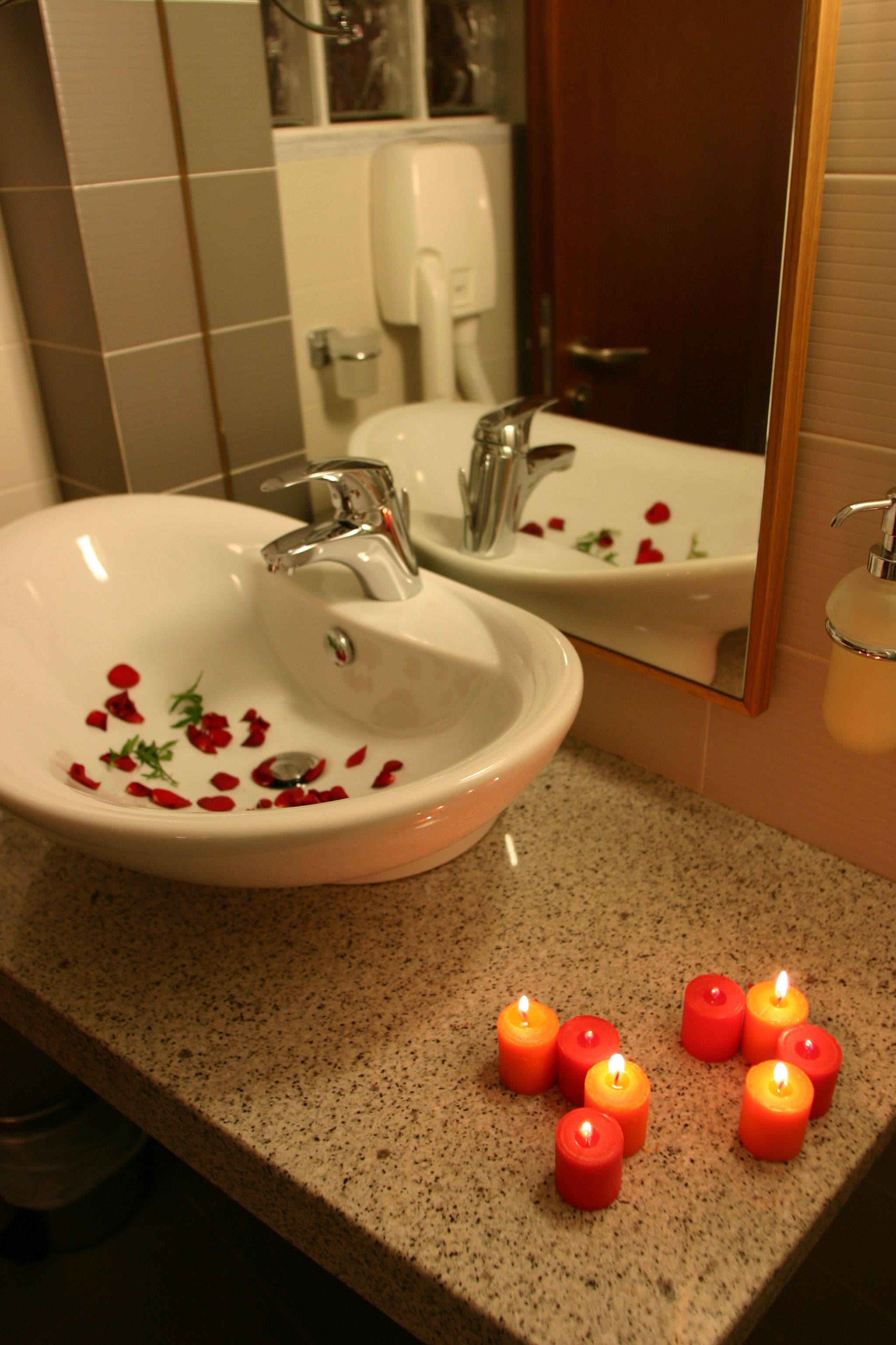 A bathroom with a white sink, a mirror, and a granite countertop.