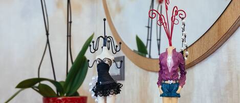 A mannequin with a purple blouse and blue shorts, a small black dress, and a red and white striped item on a wooden surface.