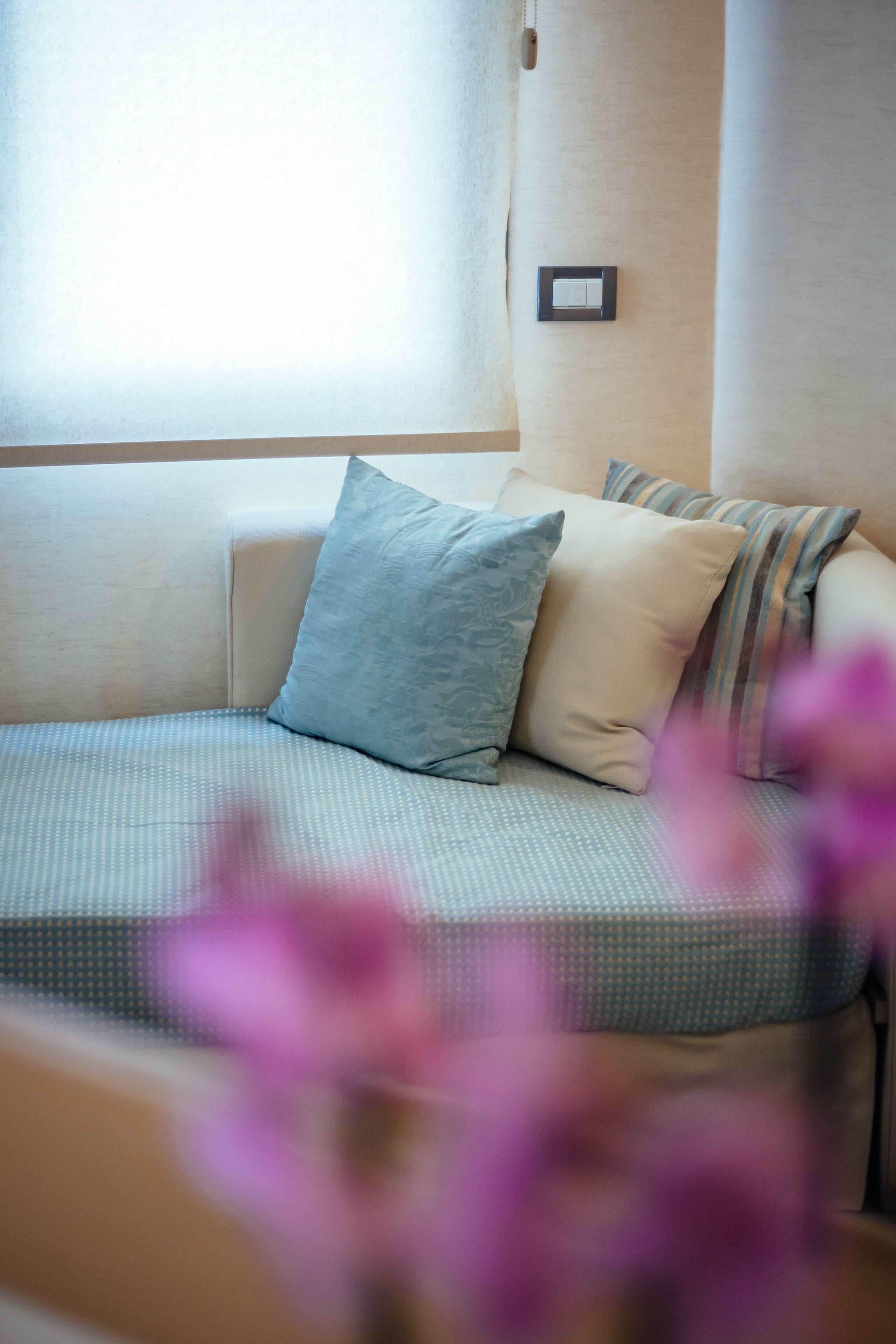 A cozy room with a sofa bed, pillows, and a wall-mounted light switch.