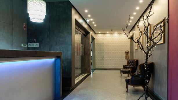 A hotel reception area with a modern design, including a reception desk, seating area, and decorative lighting. - Samasa Fundão (Fundao)