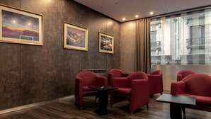 A modern interior with a seating area, framed artwork on the wall, and a view through a window. - Samasa Fundão (Fundao)