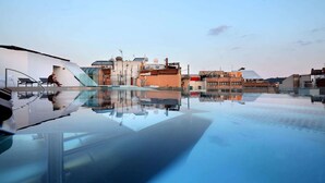 An infinity pool with a clear view of surrounding buildings and a modern architectural design.
