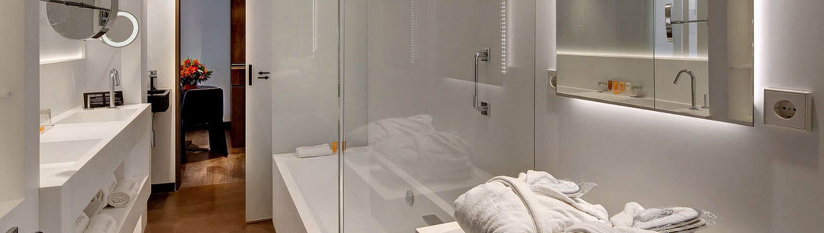 Un baño moderno con cabina de ducha de vidrio, un lavamanos blanco y un espejo sobre él.