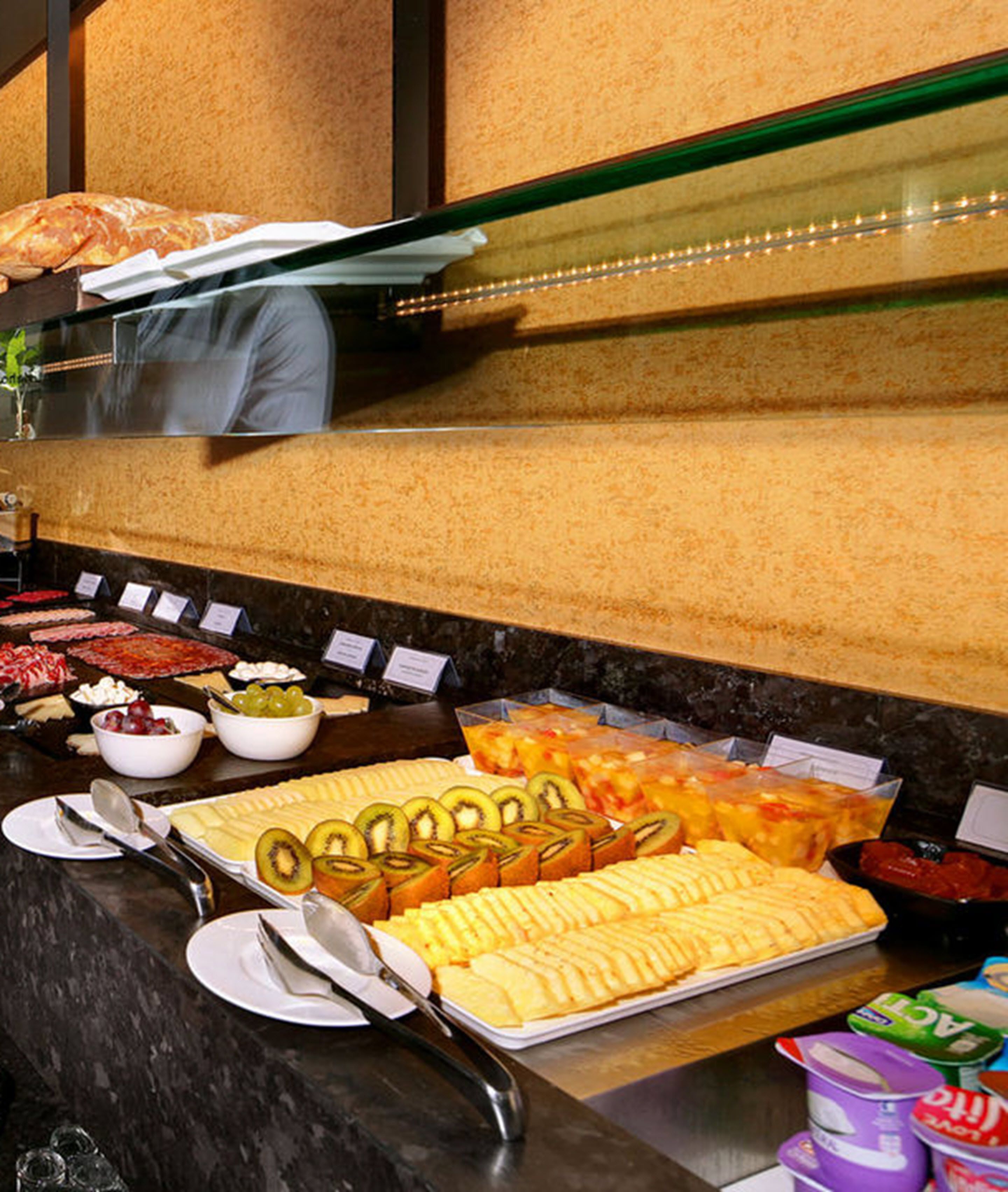 A buffet with various food items including sliced fruits, cheeses, and desserts.