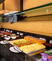 Un bufé con diversos alimentos, entre ellos frutas cortadas, quesos y postres.