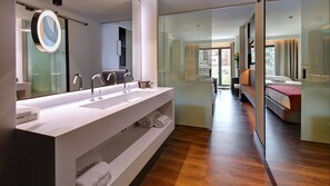 Un baño moderno con un espejo grande, tres lavamanos y un mueble de tocador con toallas.
