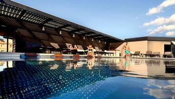A modern pool area with lounge chairs and a covered seating area.