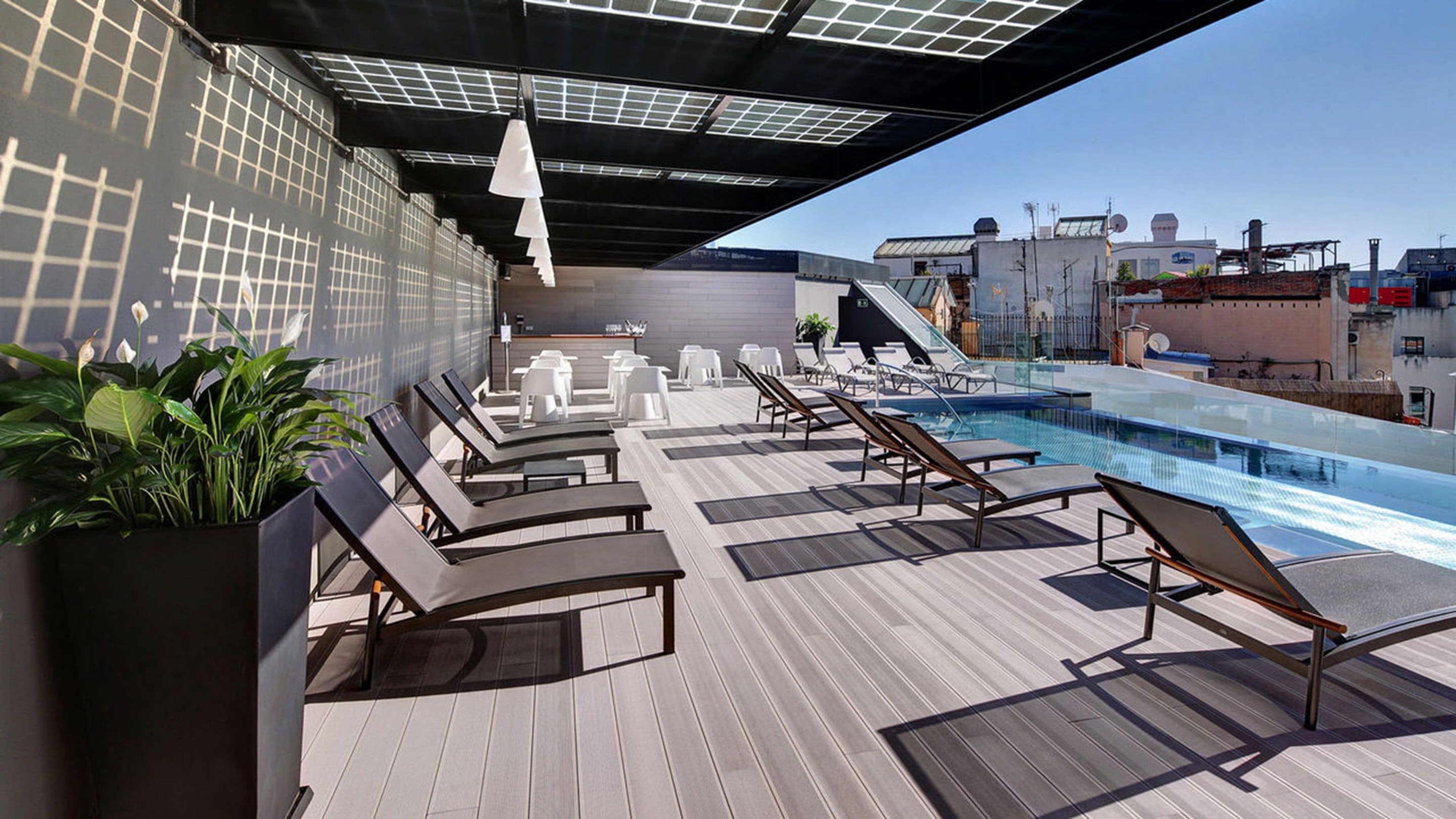 A rooftop pool area with lounge chairs, a small pool, and a view of the cityscape.