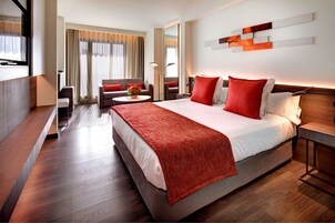Una habitación de hotel moderna con una cama grande, un sofá, un escritorio y una televisión.