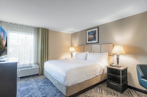 Una habitación de hotel con una cama grande, dos lámparas de noche, un escritorio con un teléfono y una silla.