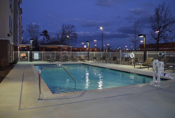 A swimming pool with a fenced deck area, surrounded by buildings and trees. - Candlewood Suites Greenville by IHG (Greenville)