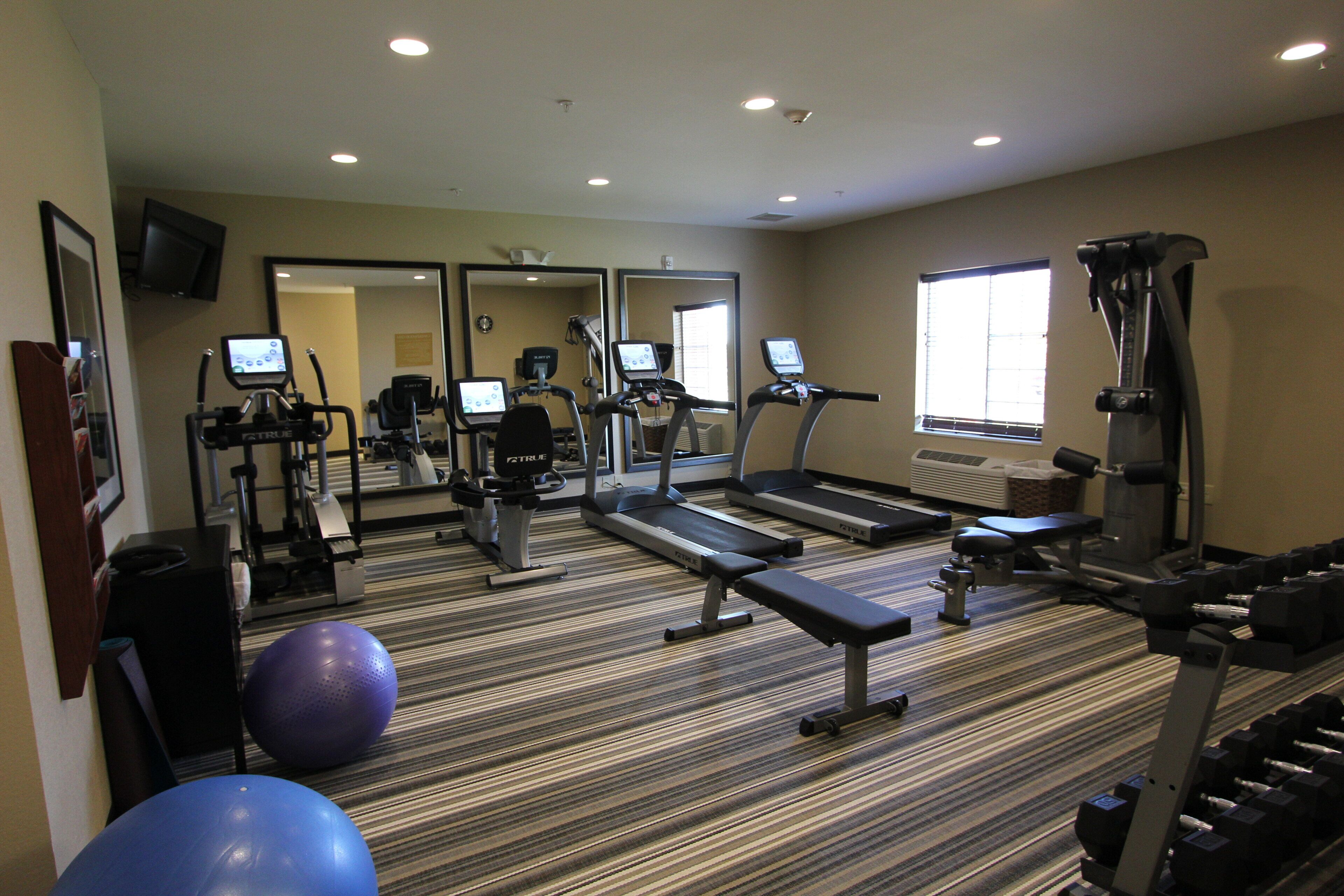 A gym with treadmills, elliptical machines, and free weights.