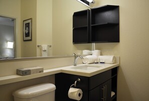 A bathroom with a white sink, a mirror, a toilet, and a black cabinet with shelves. - Candlewood Suites Greenville by IHG (Greenville)